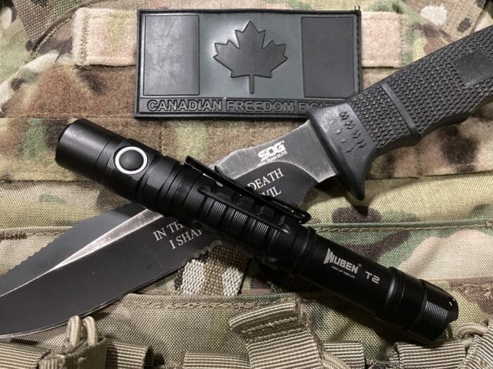 Wuben T2 Review: A Small and Powerful Backup Tactical Flashlight 2 The Wuben T2 backup tactical flashlight displayed on a condor plate carrier with a SOG SEAL team elite knife
