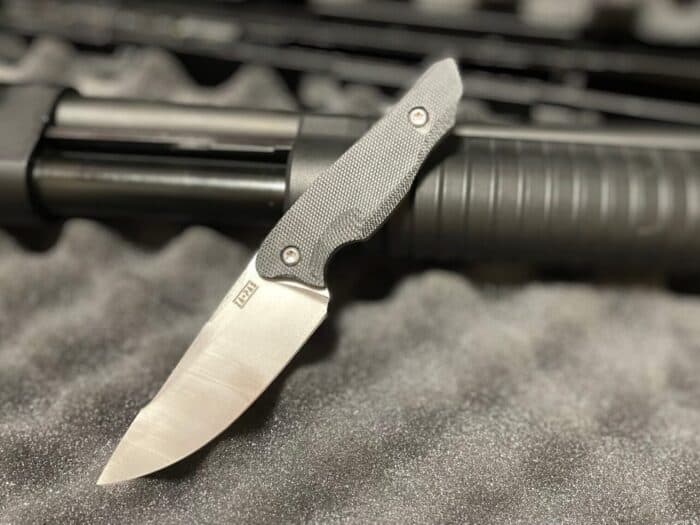 Nija Tactical Knife Review: The Polish-Built Blade Made for Self-Defense 21 the nija tactical knife by Zapas Knives leaning on a pump action shotgun